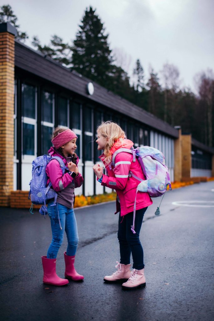 Lasten ensimmäinen puhelin. Koululaiset pihalla Xplora puhelin ranteessa. 